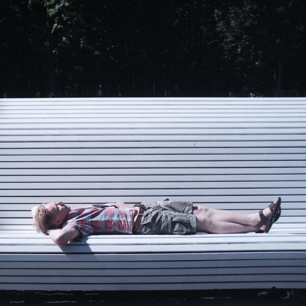man lying on bench during daytime