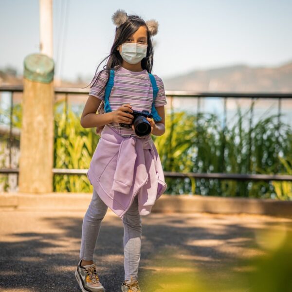 woman in white t-shirt and white pants holding black camera