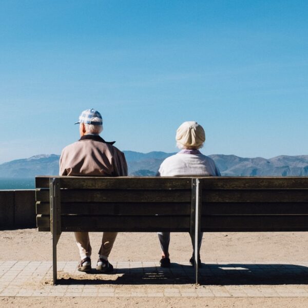 man and woman sitting on bench facing sea