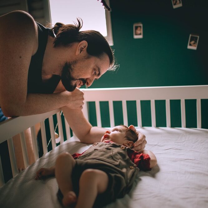 woman in black tank top carrying baby in red and white stripe onesie