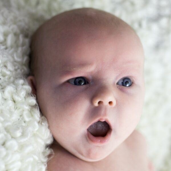 baby lying on white fur textile