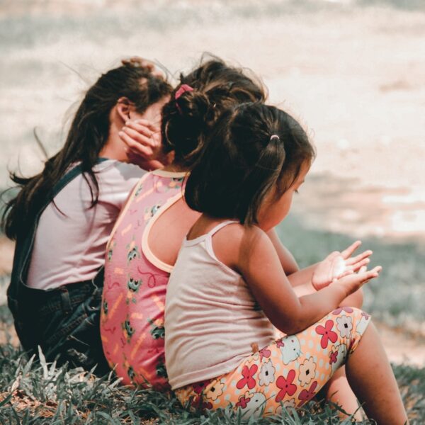 three children sitting on grass