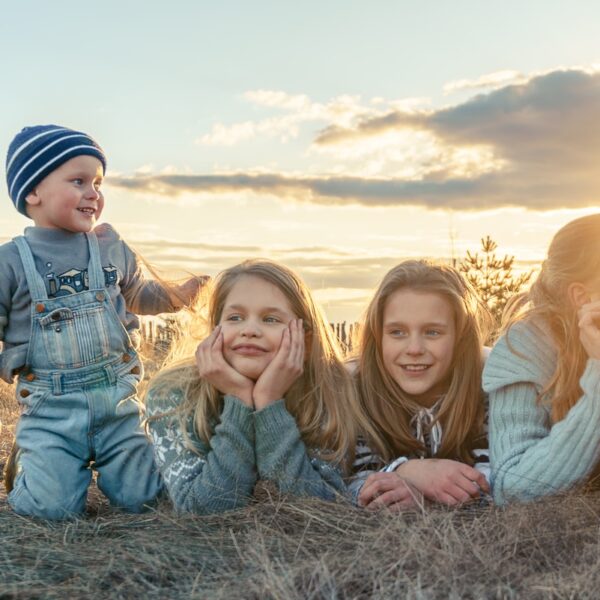 3 women sitting on grass field during sunset