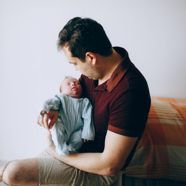 man in maroon crew neck t-shirt sitting on bed