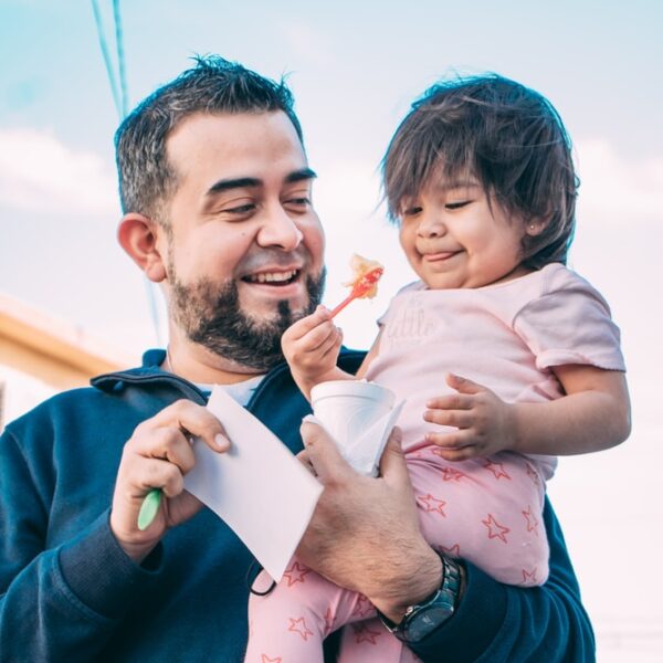 man in black jacket carrying girl in pink and white floral dress