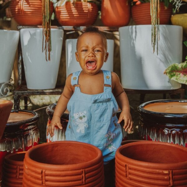 girl in blue tank top standing beside brown woven basket
