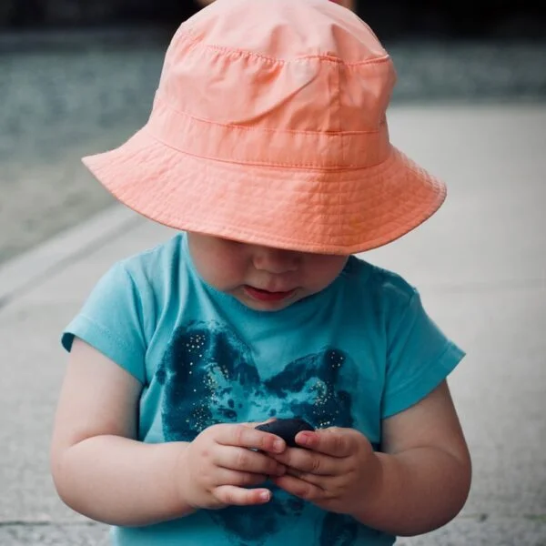 baby wearing blue shirt and orange bucket hat