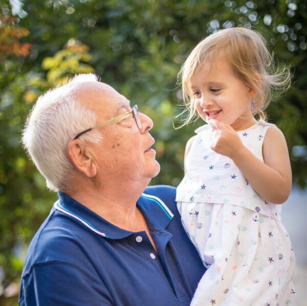 man in blue polo shirt carrying girl in white and pink floral dress
