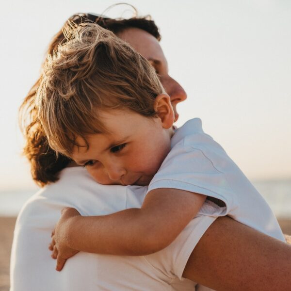 boy hugging woman during daytime