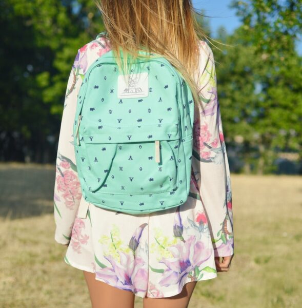 woman in white and multicolored floral long-sleeved mini dress with green backpack