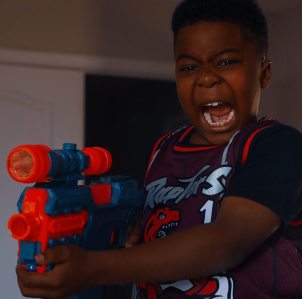 boy in black and red crew neck t-shirt holding red and black toy gun