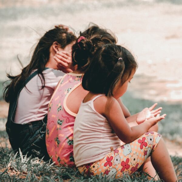 three children sitting on grass
