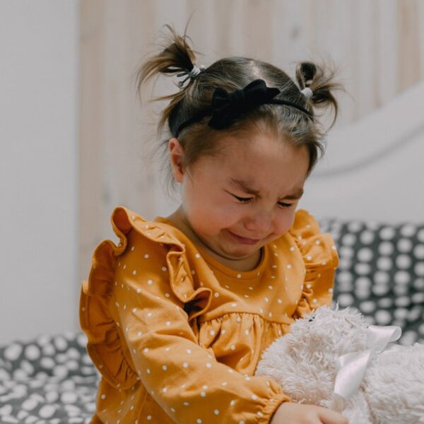 girl in orange and white polka dot long sleeve shirt sitting on white fur textile