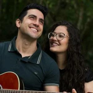selective focus photography of smiling woman beside man who play guitar during daytime